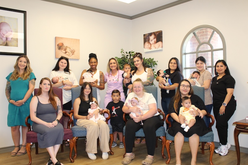 Palestine Medical Group’s Midwife Julie Quinn (center, back row, in pink scrubs) celebrates with many of her patients – new moms and moms-to-be.